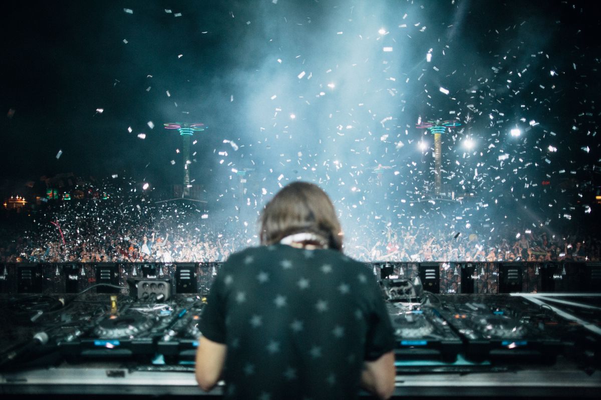 DJ a tancujúce festivalové publikum pod modrými svetlami a konfetami